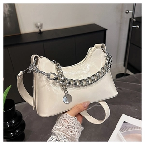 Detail of cream-white leather underarm bag with thick silver chain and metal charm decoration