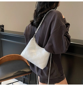 Detail einer weißen gesteppten Eimertasche aus Leder mit silbernem Kettenriemen