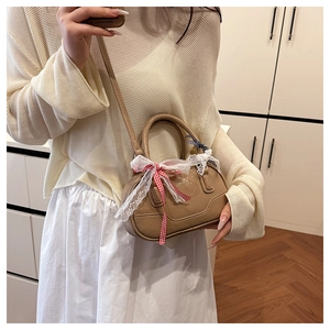 Detail view of khaki mini Boston bag with lace bow and ribbon on a model