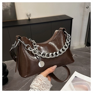 Close-up of deep brown oil wax leather underarm bag with thick silver chain and metal tag