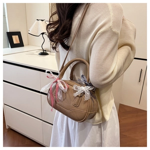 Detail of a brown PU leather Boston bag with decorative bows shown in a lifestyle setting