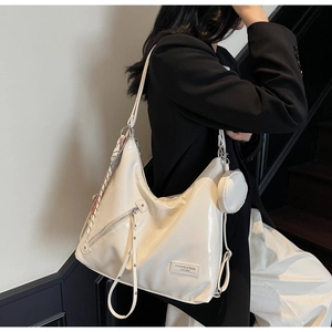 Detail of creamy white leather tote bag with silver zipper and silk scarf accessory
