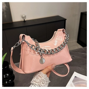 Detailed close-up of a pink patent leather shoulder bag with a silver chain strap