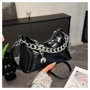 Close-up of polished black oil wax leather handbag with silver chain and metal charm