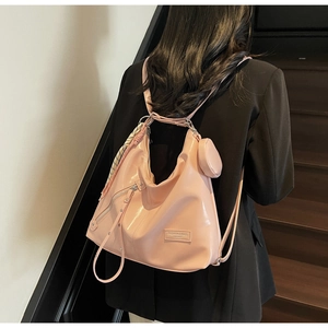 Detail of pink glossy leather tote with ribbon and round coin purse on indoor stairs