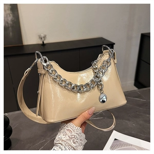 Close-up of beige oil wax leather hobo bag with bold silver chain and round pendant