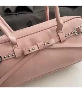 Detail of pink lychee leather bag with side bow decoration and silver metal rivets