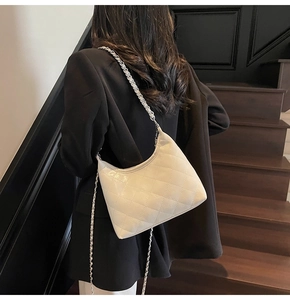 Gesteppte weiße Hobo-Tasche mit silberner Kette an der Schulter eines Models