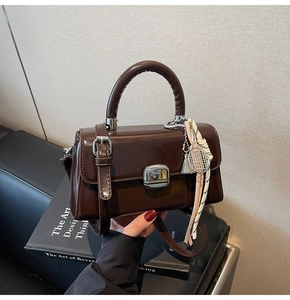 Detail of dark brown retro square handbag with metallic lock, tennis racket charm and silk scarf