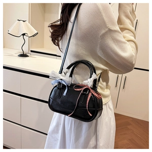 Detail of black Boston bag with colorful plaid bows and lace trim on a model