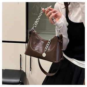 Detail view of dark brown oil wax leather underarm bag with bold silver metal chain