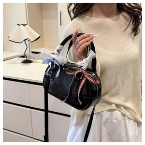 Detail of black crossbody bag with decorative lace and colorful plaid bowknots