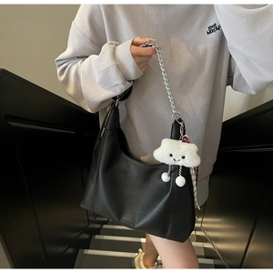 Detail of black lychee grain tote bag with silver chain strap and cloud plush charm