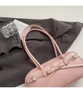 Close-up of pink shoulder bag with decorative cross-straps and metallic buckles