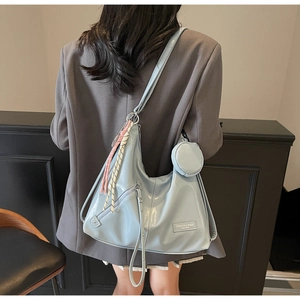 Detail of light blue hobo tote bag with round zip pouch and braided cord on a grey blazer