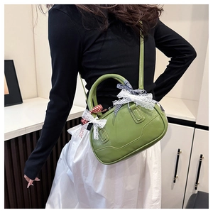 Detailed view of the green Boston bag featuring lace bows and checkered ribbon accents