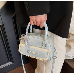 Close-up of light blue leather bowling bag with delicate lace trim and ribbon details