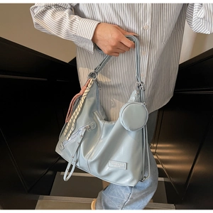 Detail of light blue crossbody bag with glossy texture, braided rope and small coin purse