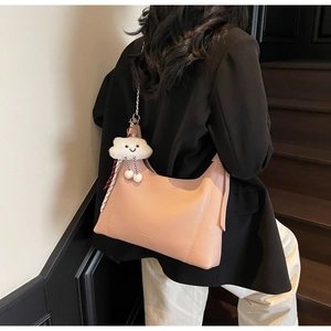 Detail of pink lychee leather hobo bag with cute white cloud plush charm and silver chain