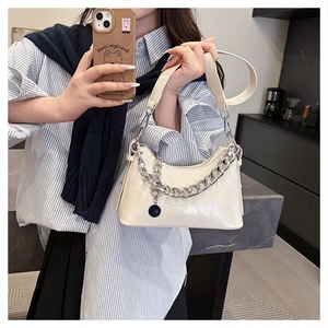 Detail of off-white faux leather underarm bag with thick silver chain and round pendant