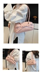 Detail view of the pale pink baguette bag featuring metal rivets and double eyelet straps