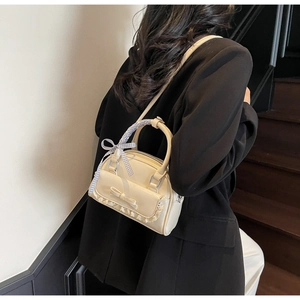 Creamy white bowling bag featuring bow tie and lace details on a female model