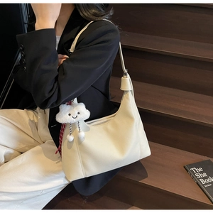 Detail of cream lychee leather crescent tote bag with cute cloud plush charm