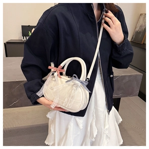 Close-up of a mini white Boston bag with lace and plaid bows worn by a model
