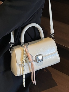 Minimalist cream patent leather crossbody bag with silver buckle and braided rope charm