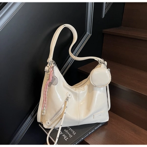 Close-up of cream patent leather tote with a small round pouch on a dark wood stairs