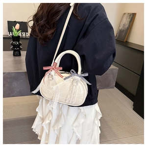 Detail showing creamy white bowling bag with lace and bow charms worn by a model