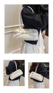 Detailed view of cream leather underarm bag featuring a modern bow buckle design