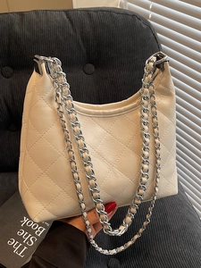 Gesteppte beige Beuteltasche mit silberner Kette in einer stilvollen Lifestyle-Umgebung