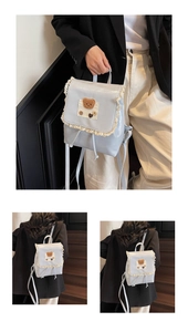 Detail of light blue backpack featuring lace trim, plush bear patch, and drawstring closure