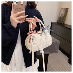 Detail of cream white Boston bag featuring delicate lace trim and colorful plaid bows