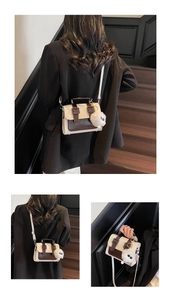 Detail view of British style ivory and brown crossbody bag with plush charm and dual buckles