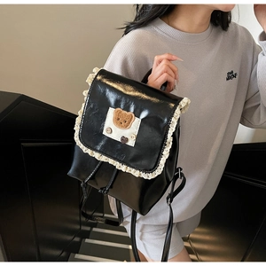 Close-up of black PU leather backpack with lace trim, embroidery, and bear accent