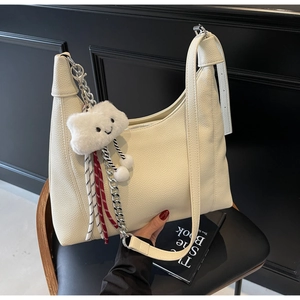 Detail of creamy white lychee grain leather hobo bag with silver chain and plush charm