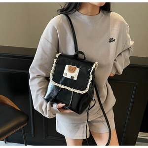 Detail of cute black PU leather backpack with lace trim and plush bear patch shown on model