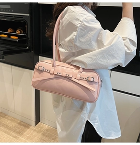 Detailed side view of a glossy pink shoulder bag featuring silver buckle straps