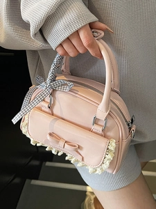 Pink ballet-style bowling bag with lace trim and bow charm held by a model
