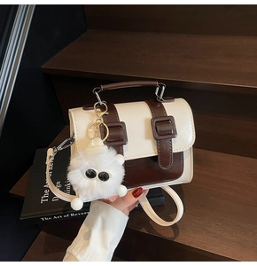 British style vintage satchel bag with plush monster charm on brown wooden stairs
