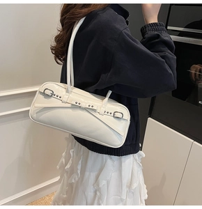 Detail of a creamy white leather shoulder bag with silver buckle and rivet accents