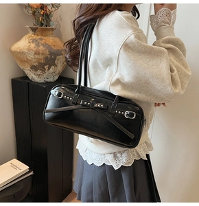 Detail of a retro black leather shoulder bag with bow buckle decoration on a model