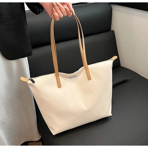 Detail view of large cream nylon tote bag with brown faux leather straps and zipper
