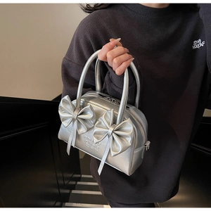 Gros plan d'un sac Boston argenté avec nœuds et détails en cuir métallisé chic
