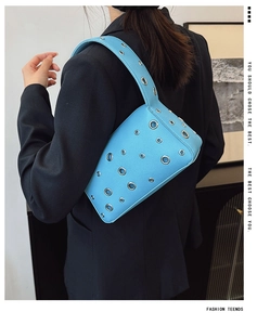 Macro detail of light blue pebble leather underarm bag with silver metal eyelets