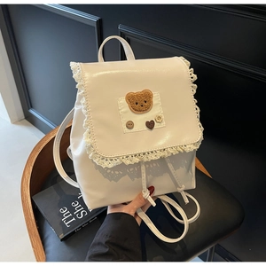 Detail of creamy white PU leather backpack with lace trim and plush bear patch decoration
