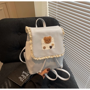 Detail of light blue PU leather backpack featuring lace trim and teddy bear patch