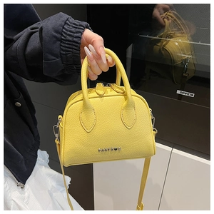 Close-up of yellow litchi grain leather bag with silver metal logo and dual handles